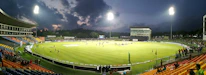 Close-up of a cricket ball hitting the bat under stadium lights.