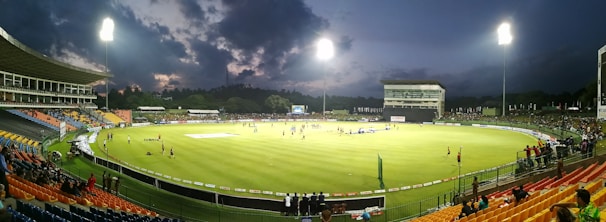 A vibrant stadium under floodlights with fans cheering during a T20 cricket match.