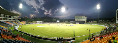Close-up of a cricket ball hitting the bat under stadium lights.