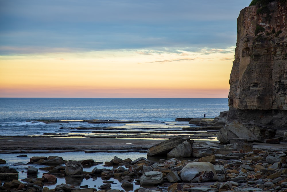 a person standing on a rocky beach next to the ocean