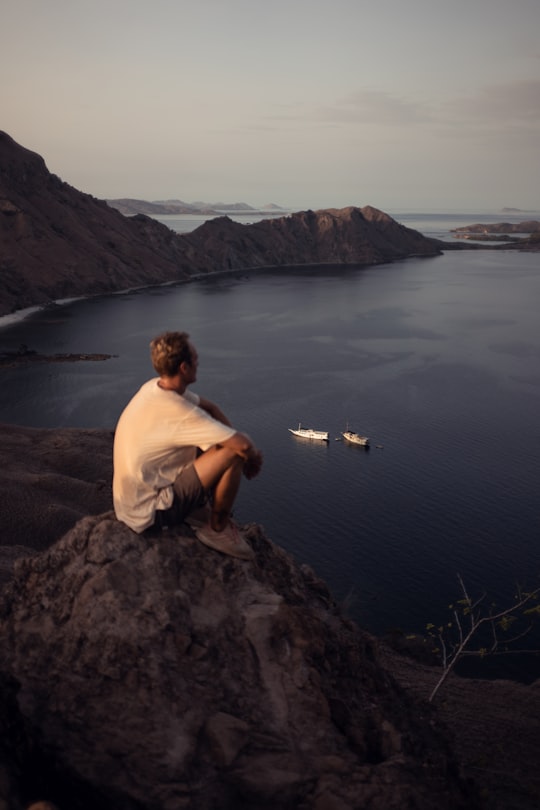 man sitting on cliff in Komodo National Park Indonesia