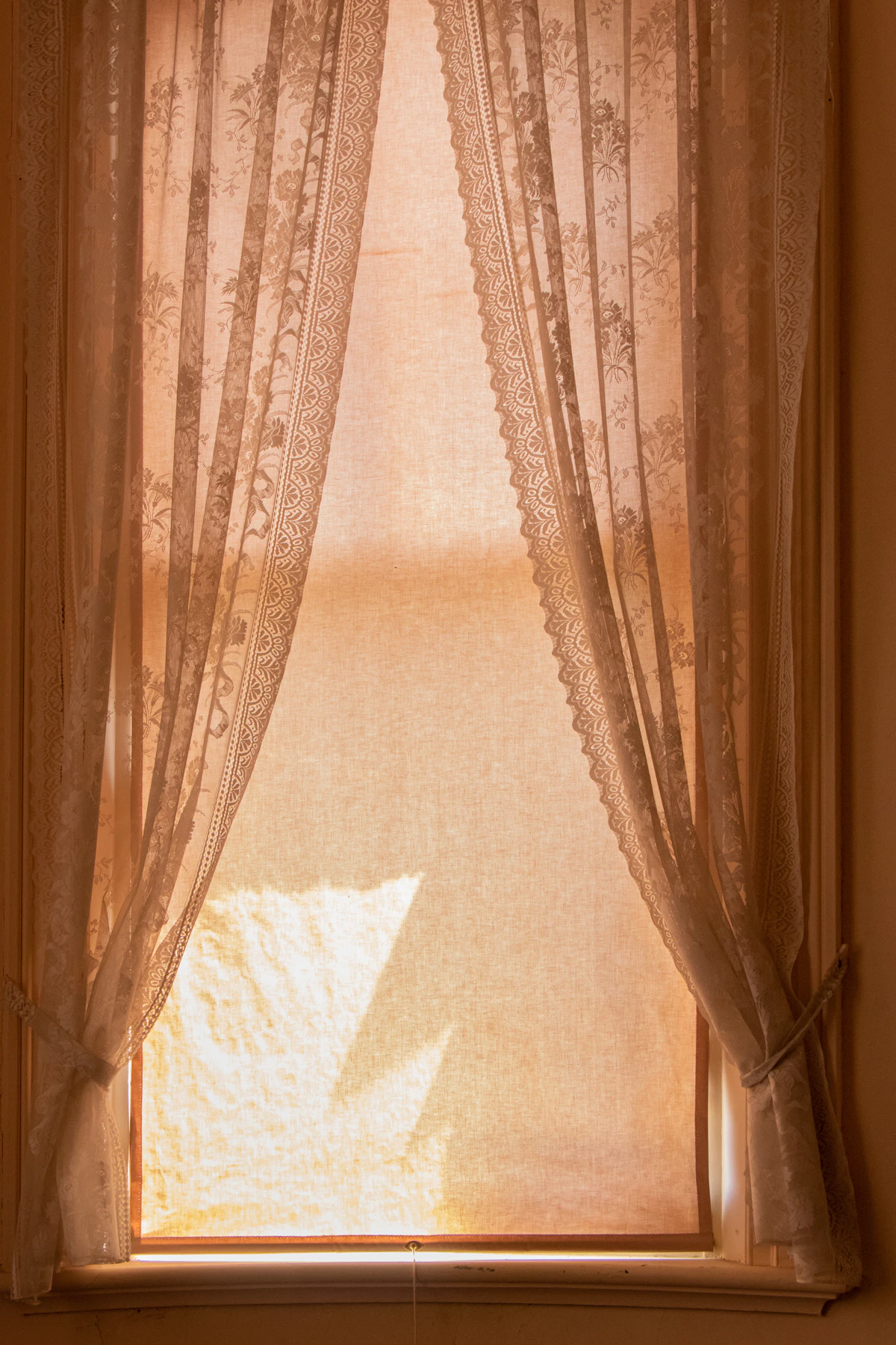 Lumière chaude du jour traversant des rideaux de dentelle