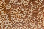 Intricate patterns of floral and foliage designs are carved elegantly into a surface, with detailed depictions of leaves, flowers, and fruits intertwined across the textured background. The craftsmanship reflects a harmonious blend of natural elements creating a vintage or classical aesthetic.