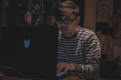 A friendly person typing on a laptop with election maps of Bangladesh in the background.