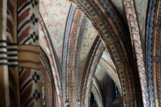 Intricate architectural arches adorned with detailed, symmetrical patterns and motifs. The design features a combination of floral and geometric patterns in muted tones that create a harmonious and historic atmosphere.