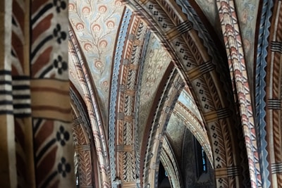 Intricate architectural arches adorned with detailed, symmetrical patterns and motifs. The design features a combination of floral and geometric patterns in muted tones that create a harmonious and historic atmosphere.