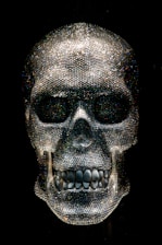 A dimly lit exhibit showcasing glowing crystal skulls resting on velvet cushions.