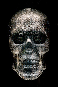 A glowing crystal skull resting on a velvet cushion inside a softly lit museum display.