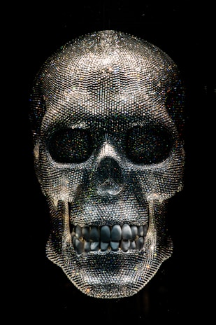 A dimly lit exhibit showcasing glowing crystal skulls resting on velvet cushions.