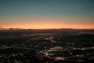 A sweeping vista of Ceikeinu’s five central cities under a twilight sky, each city distinct yet connected by glowing ley lines.