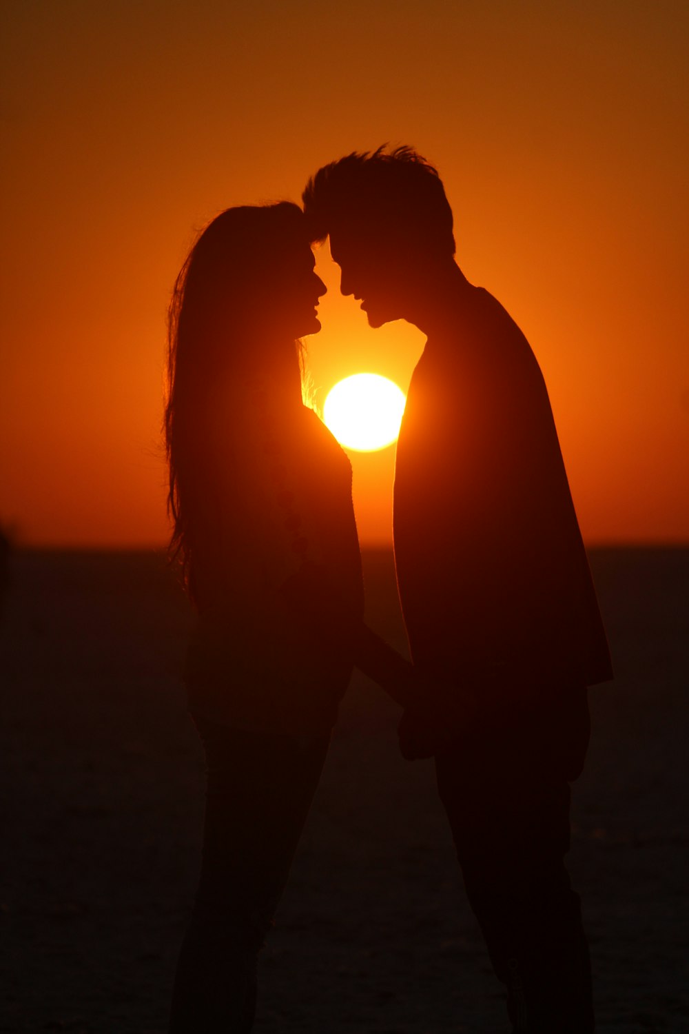 silhouette of man and woman holding hands under the sun