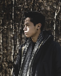 man in black coat standing near trees