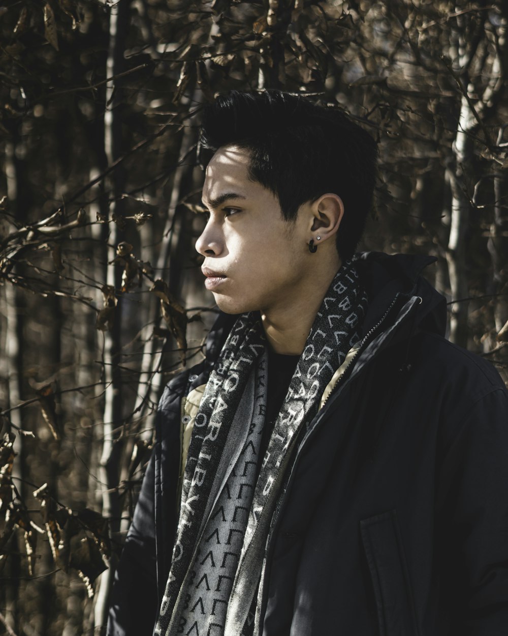 man in black coat standing near trees