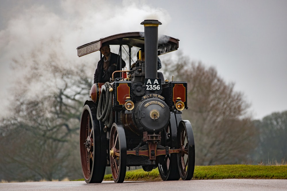 an old fashioned steam engine driving down a road