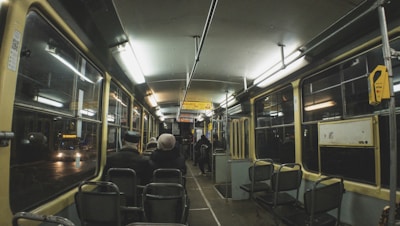 A sleek modern shuttle bus driving through a city street at dusk with warm interior lighting.