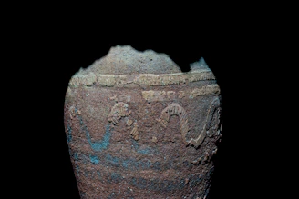 Close-up of a weathered antique pottery vase with intricate patterns.