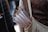 A quiver filled with numerous wooden arrows, each featuring a white tail feather. The person carrying the quiver is wearing a leather garment, likely a protective vest, decorated with small brass studs.