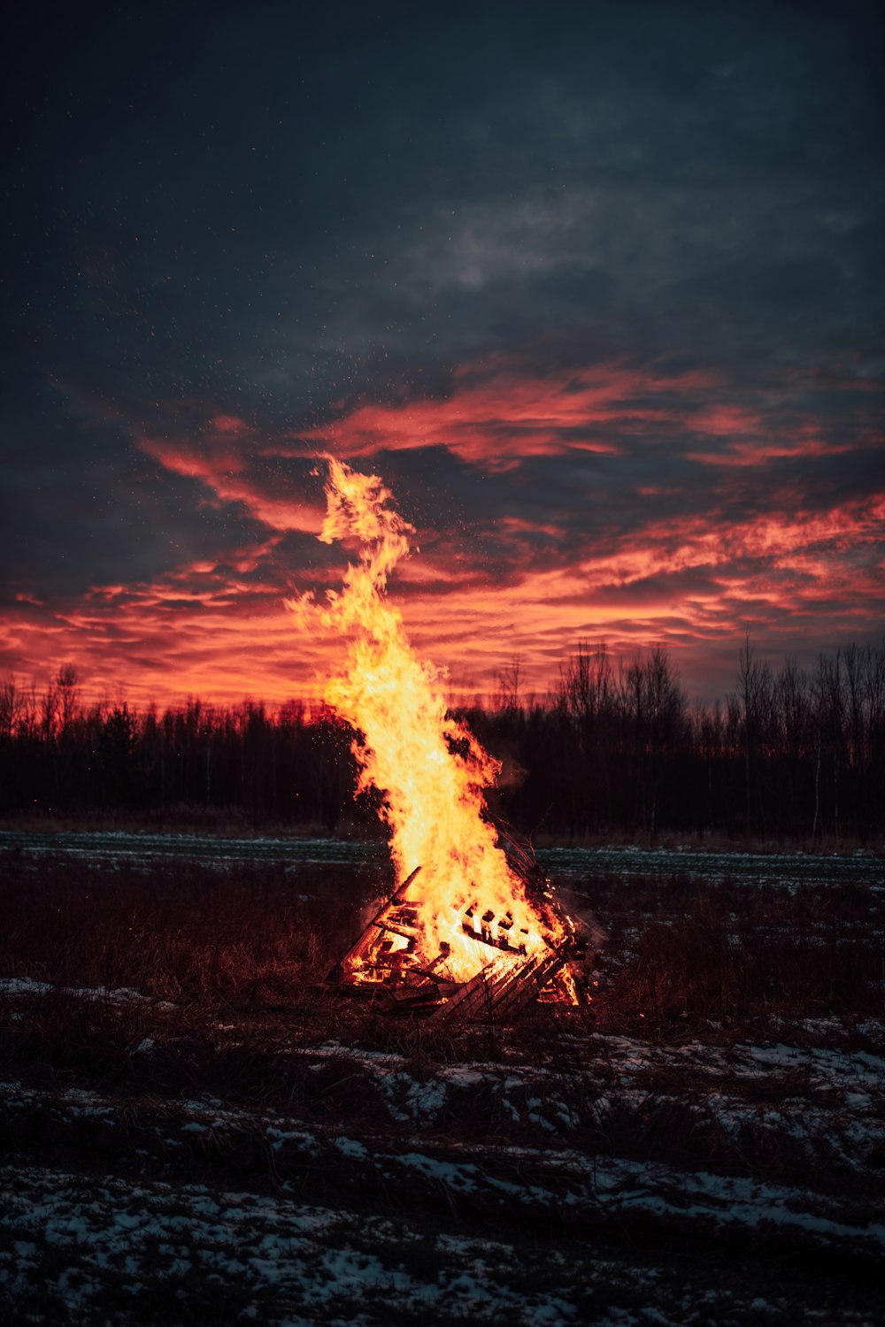 a bonfire in the middle of a field at sunset