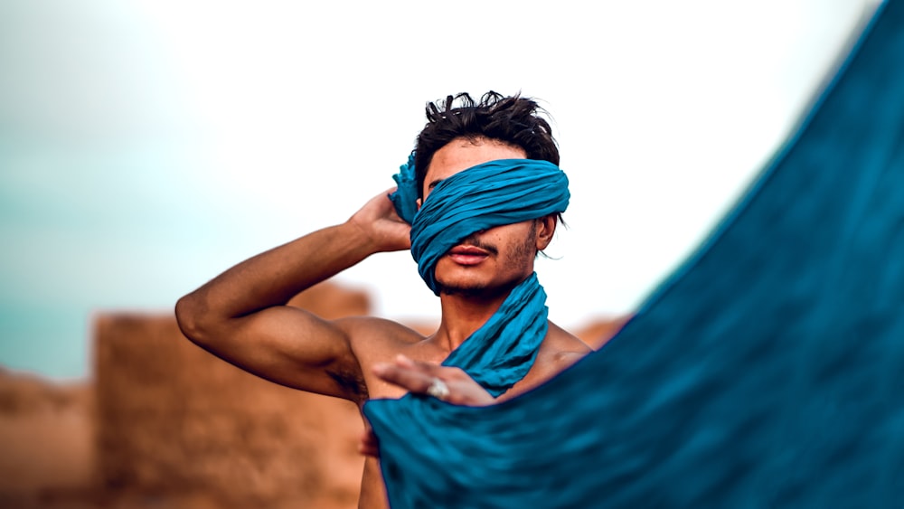 topless man holding blue textile