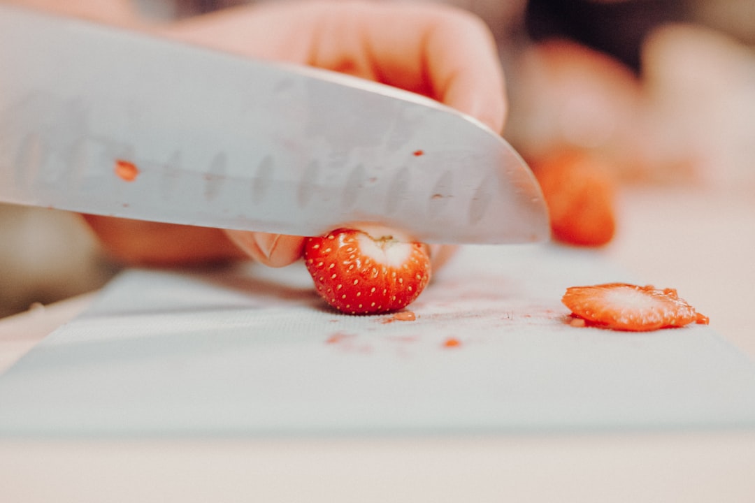 person slicing strawberry fruit