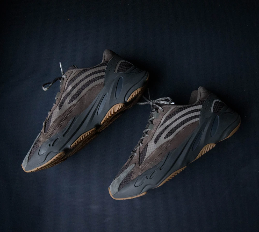 Пара серых раннеров Yeezy 700 с каучуковой подошвой на тёмно-синем фоне