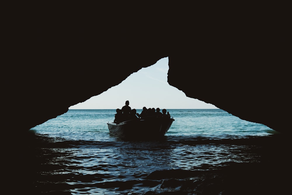 people riding in boat on body of water under blue and white sky