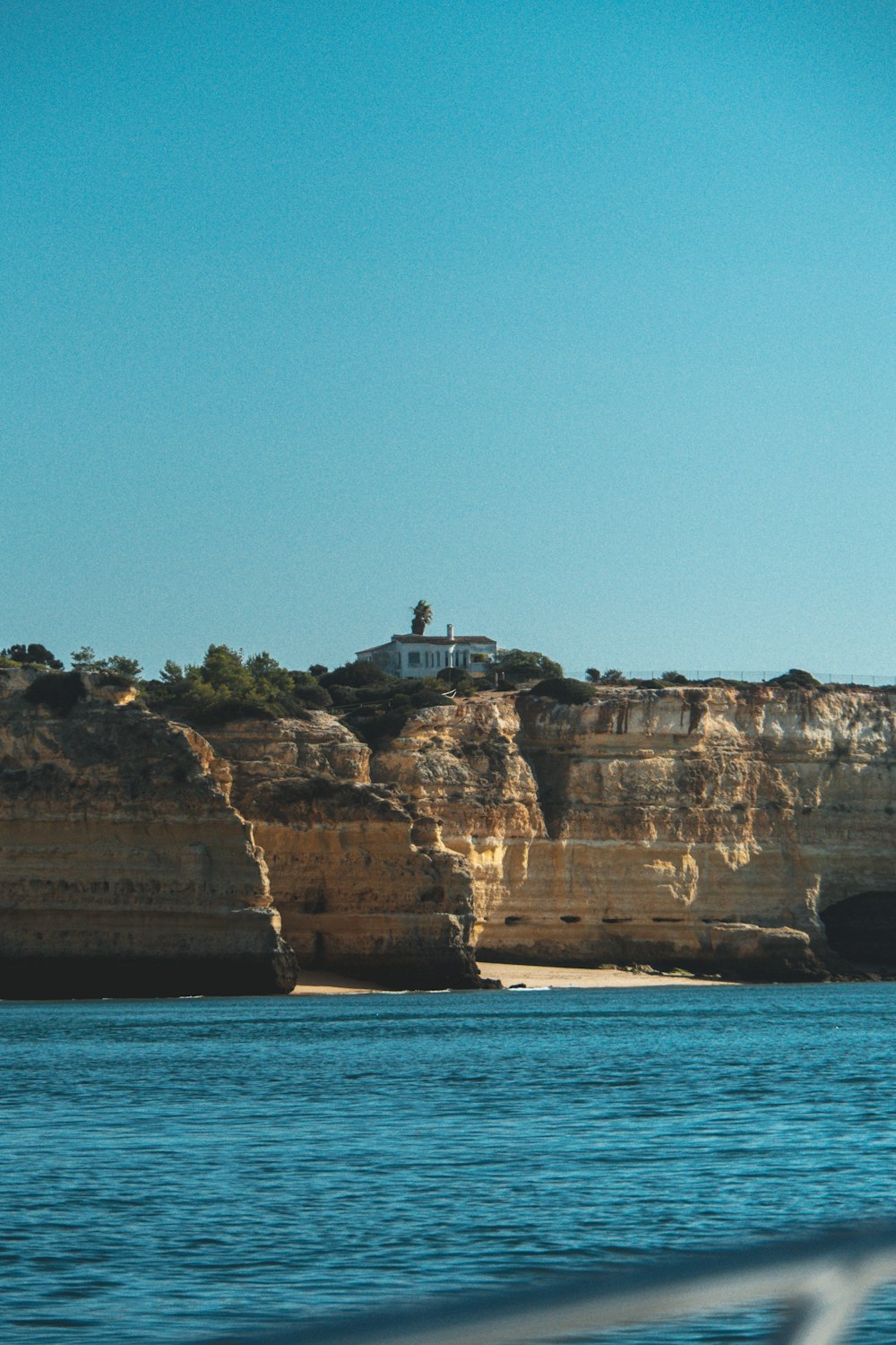 building on cliff viewing mountain blue body of water