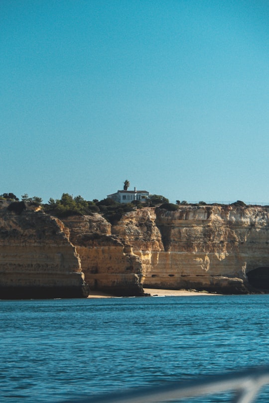 building on cliff viewing mountain blue body of water in Carvoeiro Portugal