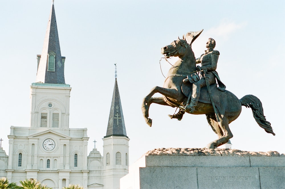 man riding on horse statue near white concrete building