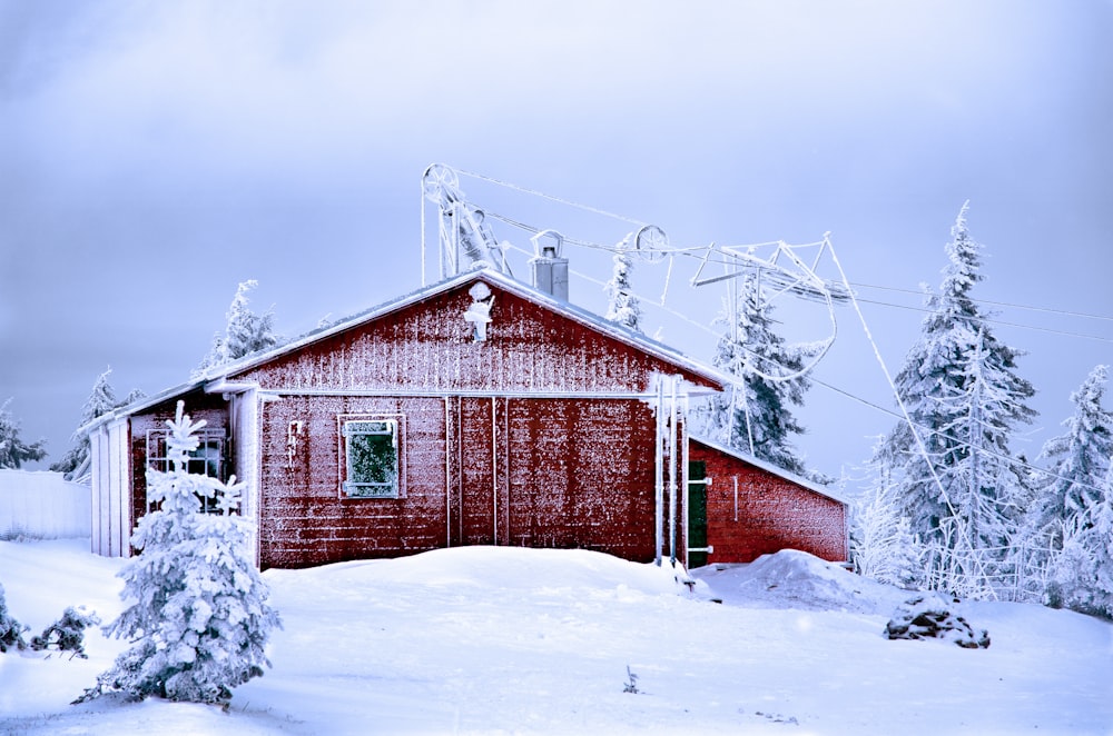 snow covered red and gray house surrounded by trees during daytime