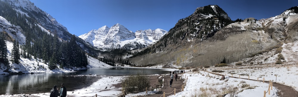 body of water beside snow covered rocky mountain during daytime