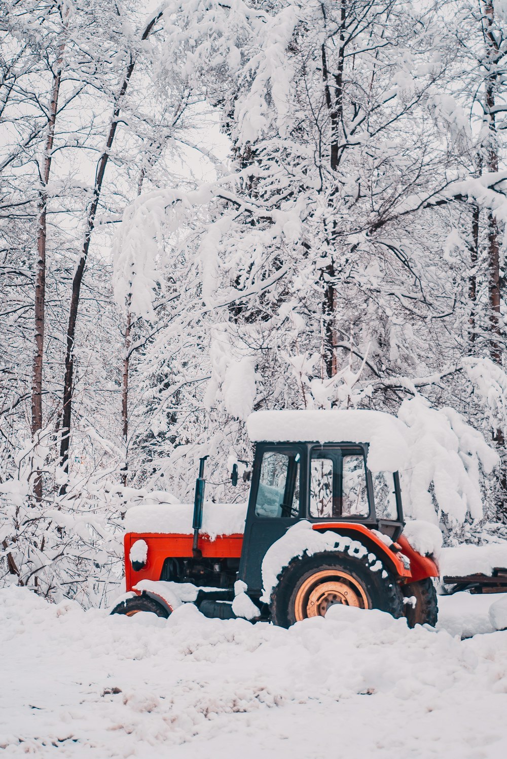 snow covered parked red and black tractor