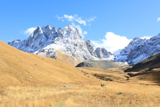 Snow-capped mountains with adventurers hiking along a scenic trail