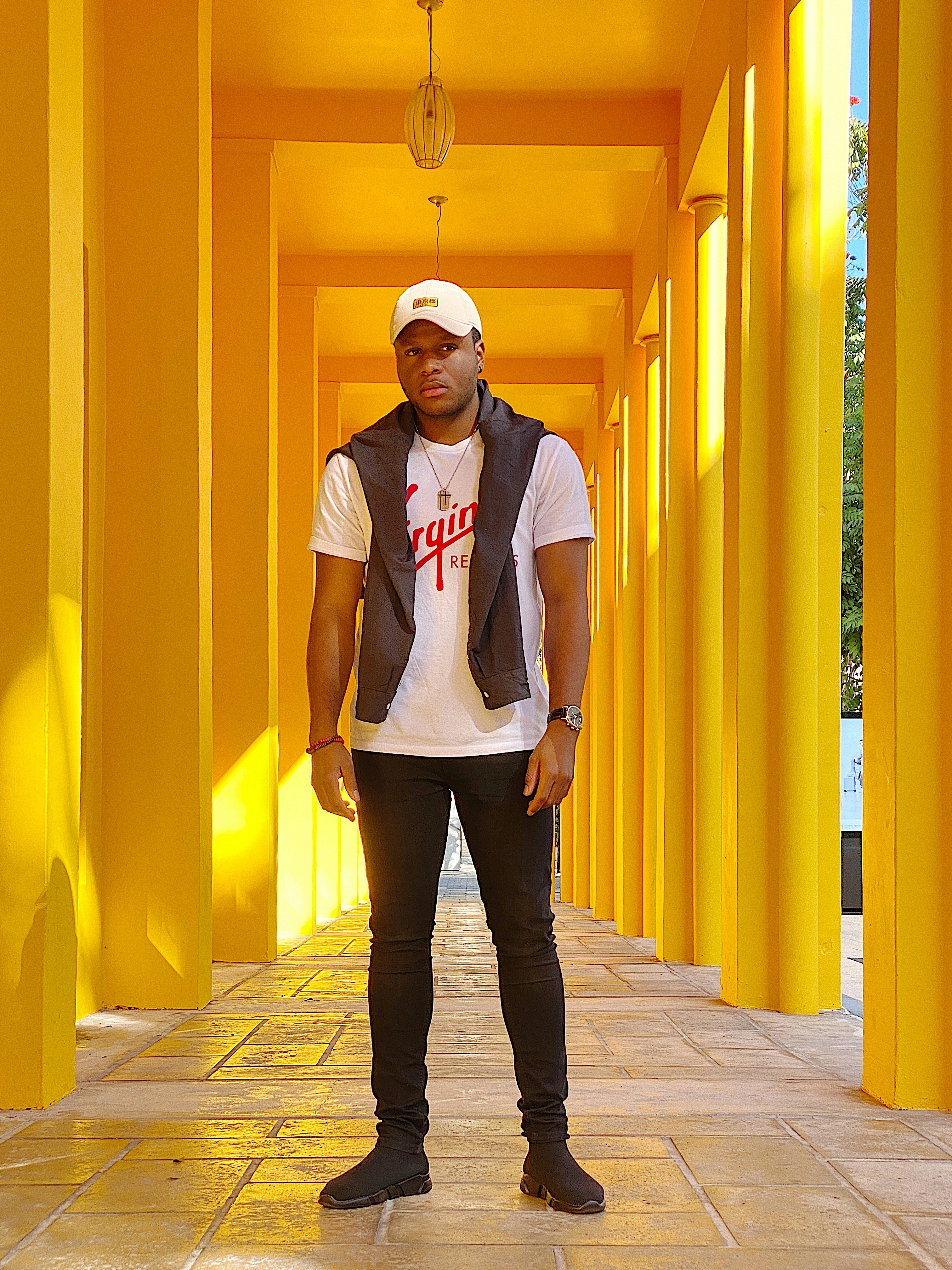 man wearing white and red Virgin crew-neck t-shirt and white hat standing on tiled hallway