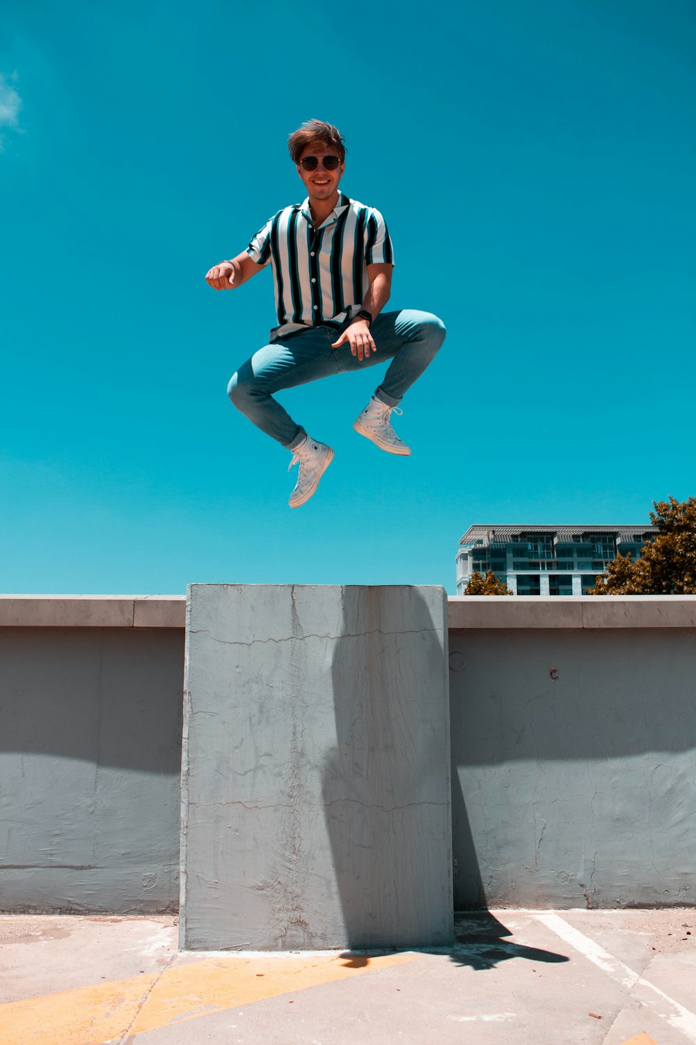 man in mid air above concrete floor and fence during day