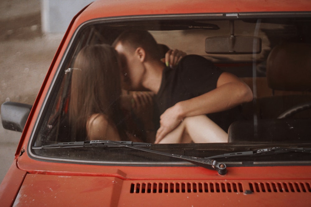 kissing man and woman inside red car