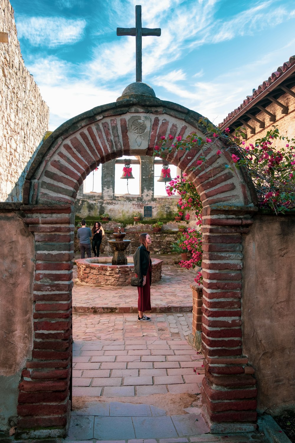 woman standing beside arch pathway with cross