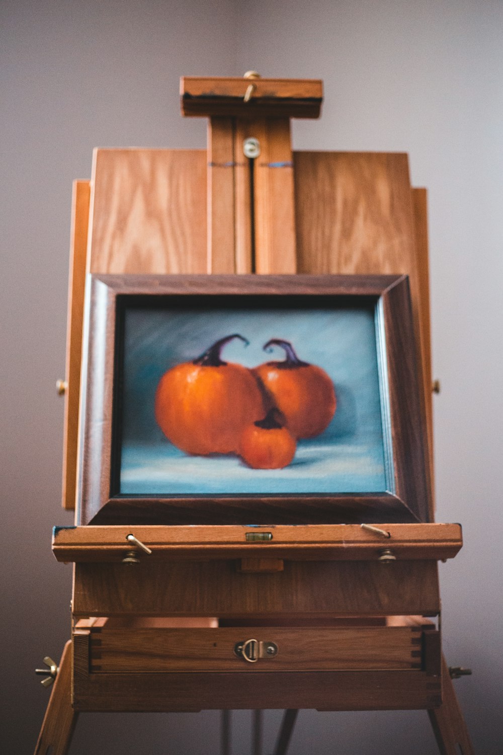 three pumpkins painting on easel