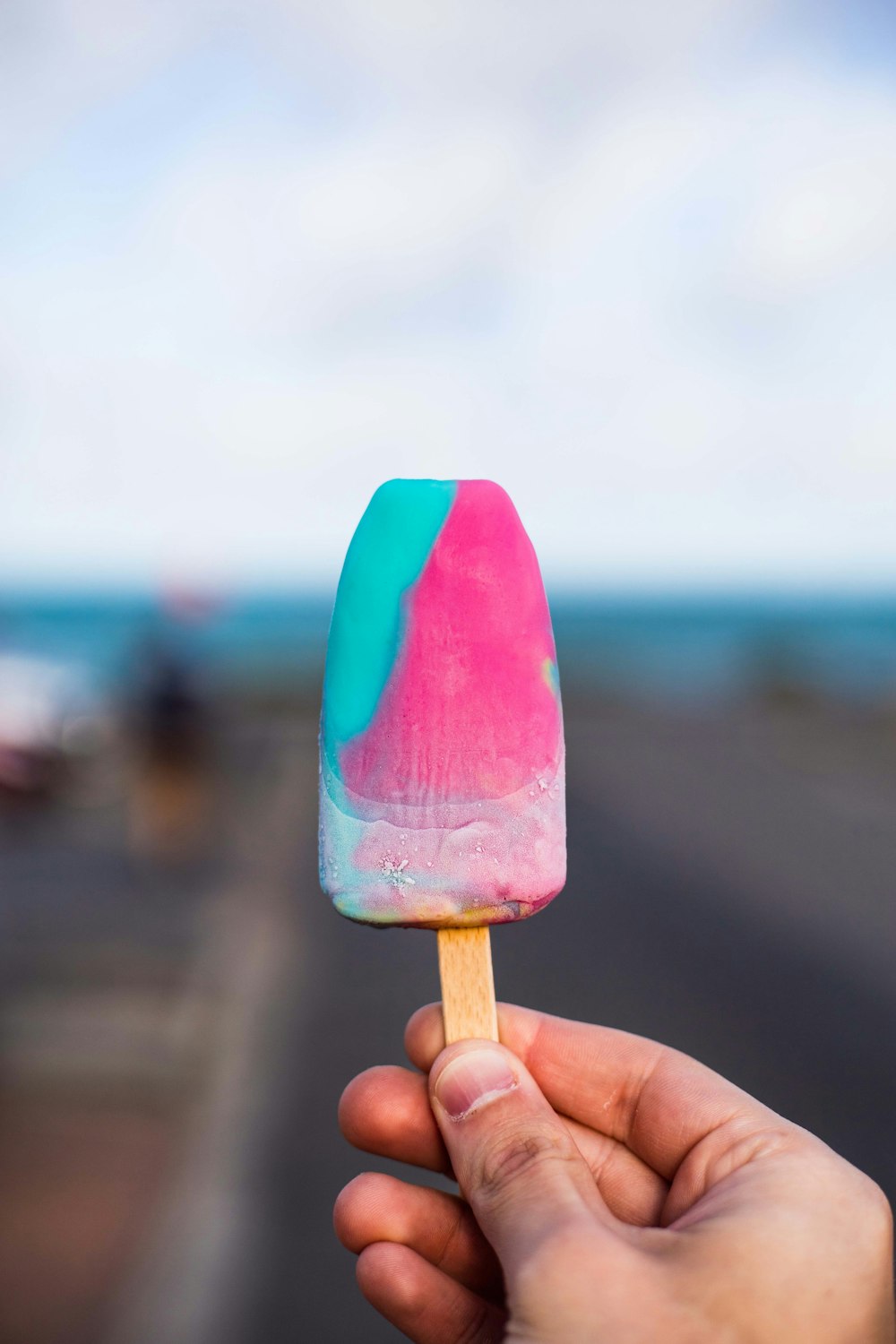 person holding purple and blue popsicle