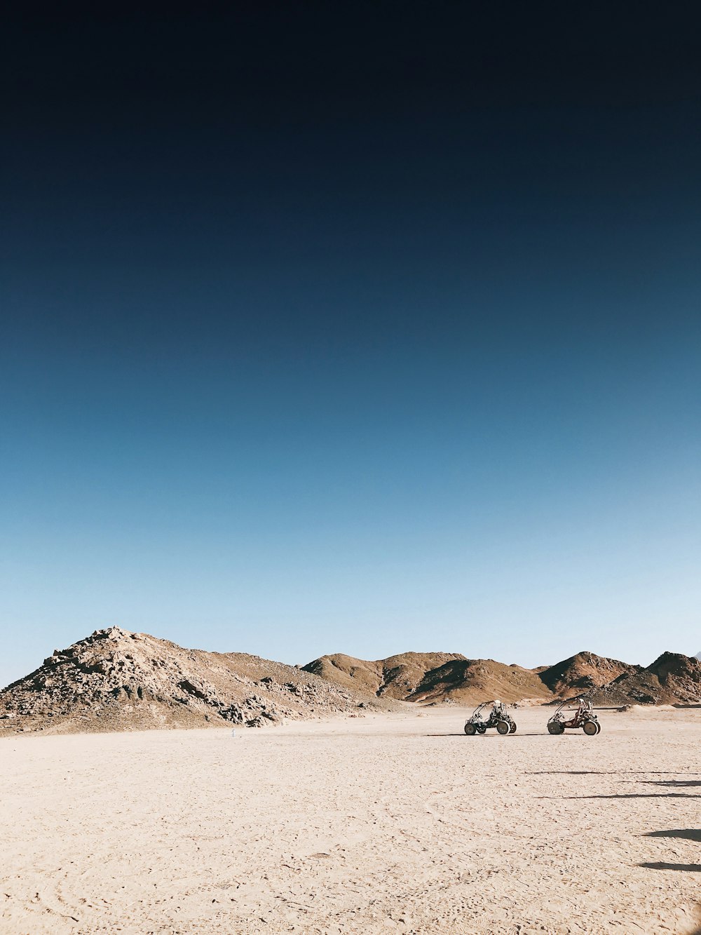 Un grupo de vehículos de cuatro ruedas conduciendo a través de un desierto
