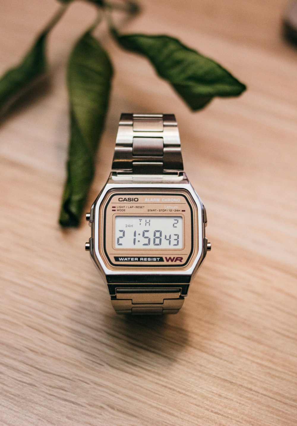 brown and silver Casio digital watch on wooden surface