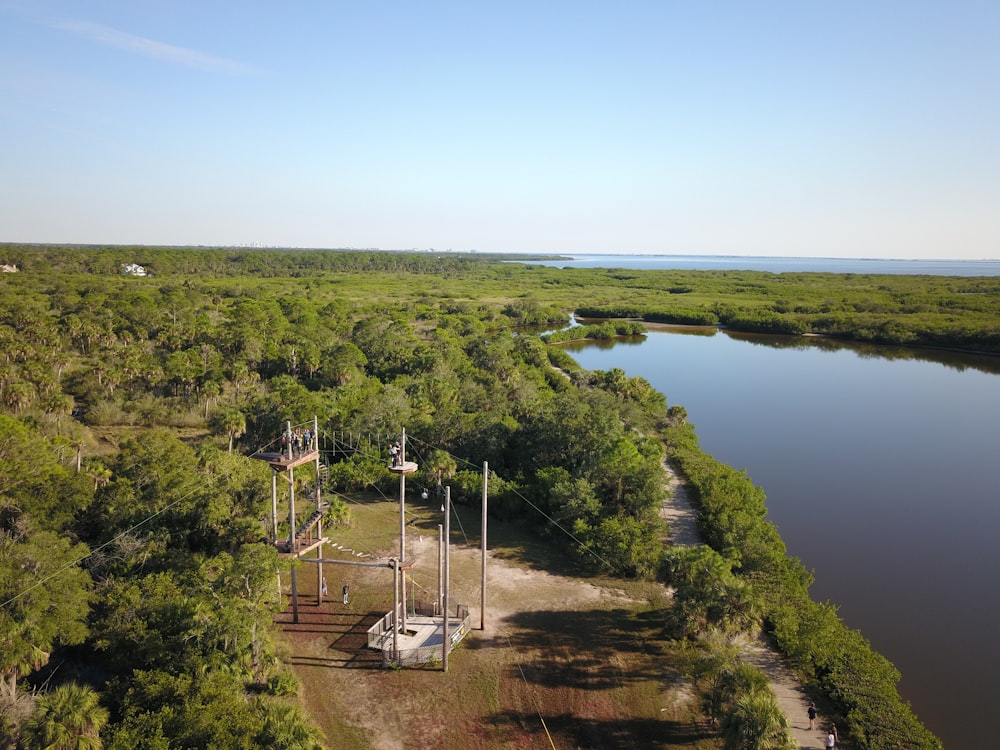 gray transmission tower beside trees and river during daytime