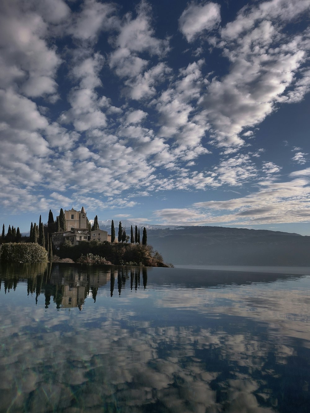 grey house near the body of water under white clouds