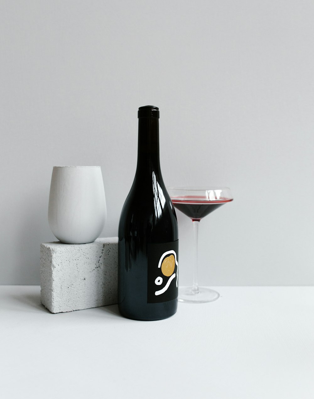black wine bottle beside wineglass