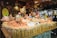 A festive market stall displays a variety of fresh eggs piled on straw, surrounded by decorative ceramic chickens. The wooden stall is adorned with rustic decorations, creating a quaint village market atmosphere.