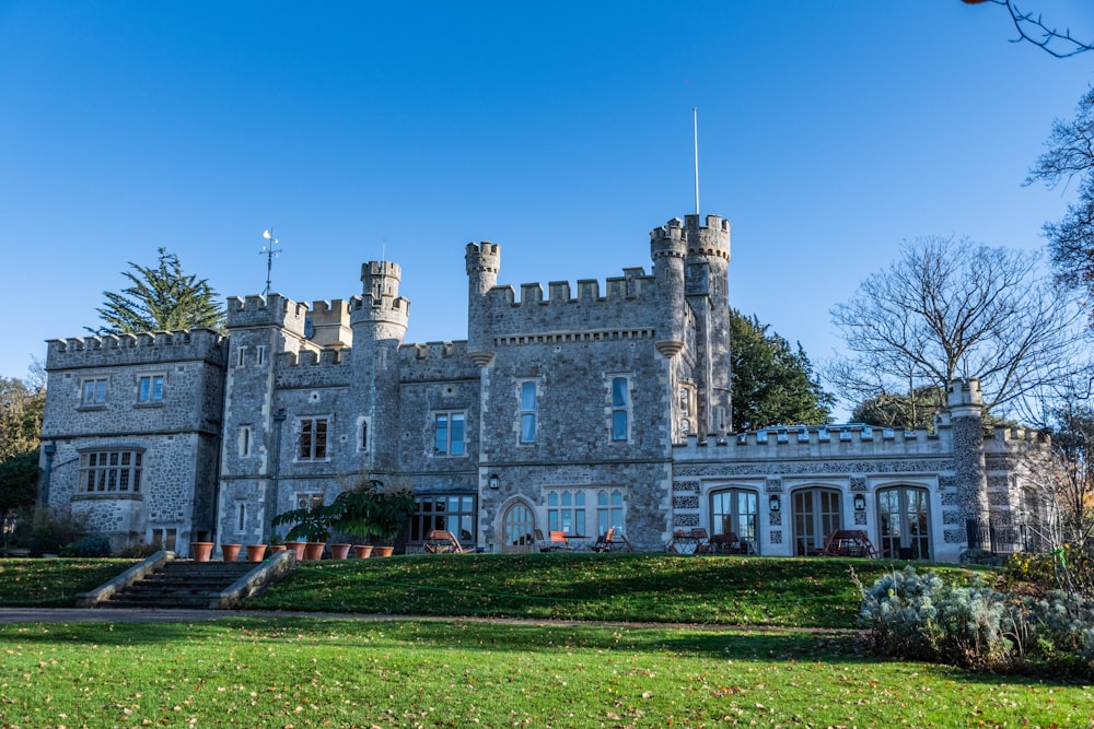 Un gran castillo como un edificio sentado en la cima de un exuberante campo verde