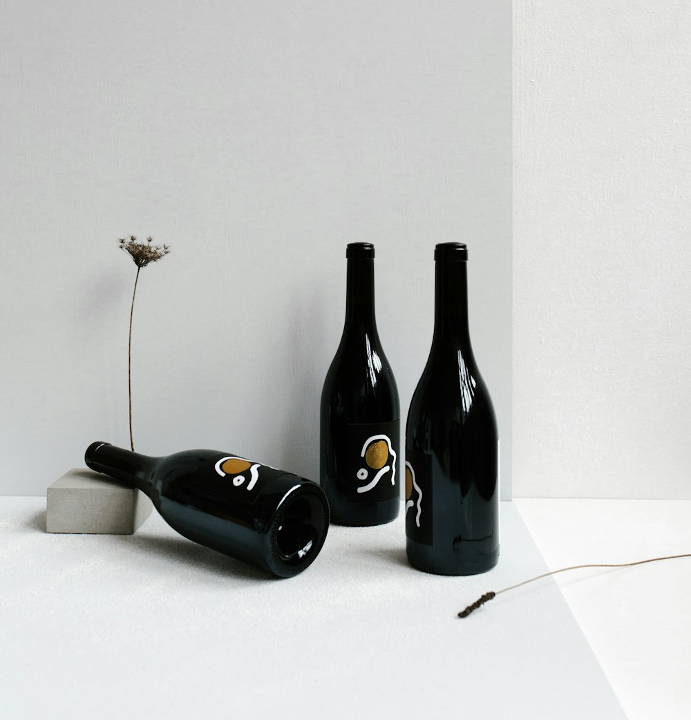 three black bottles on white surface