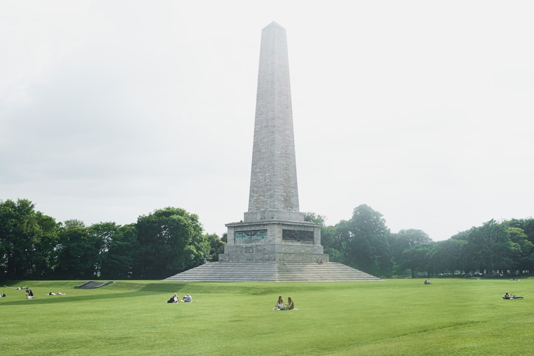 people sitting on field near obelisk monument during daytime