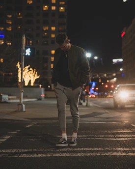 Model walking the city streets at night wearing eclipse tailored joggers with a blurred urban backdrop