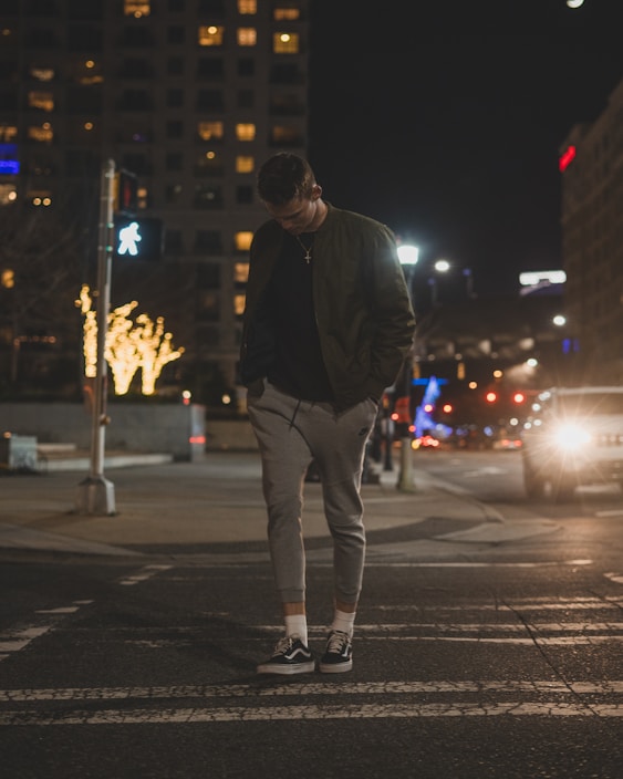Dynamic shot of a person walking in sleek black cargo pants with city lights blurred in the background.